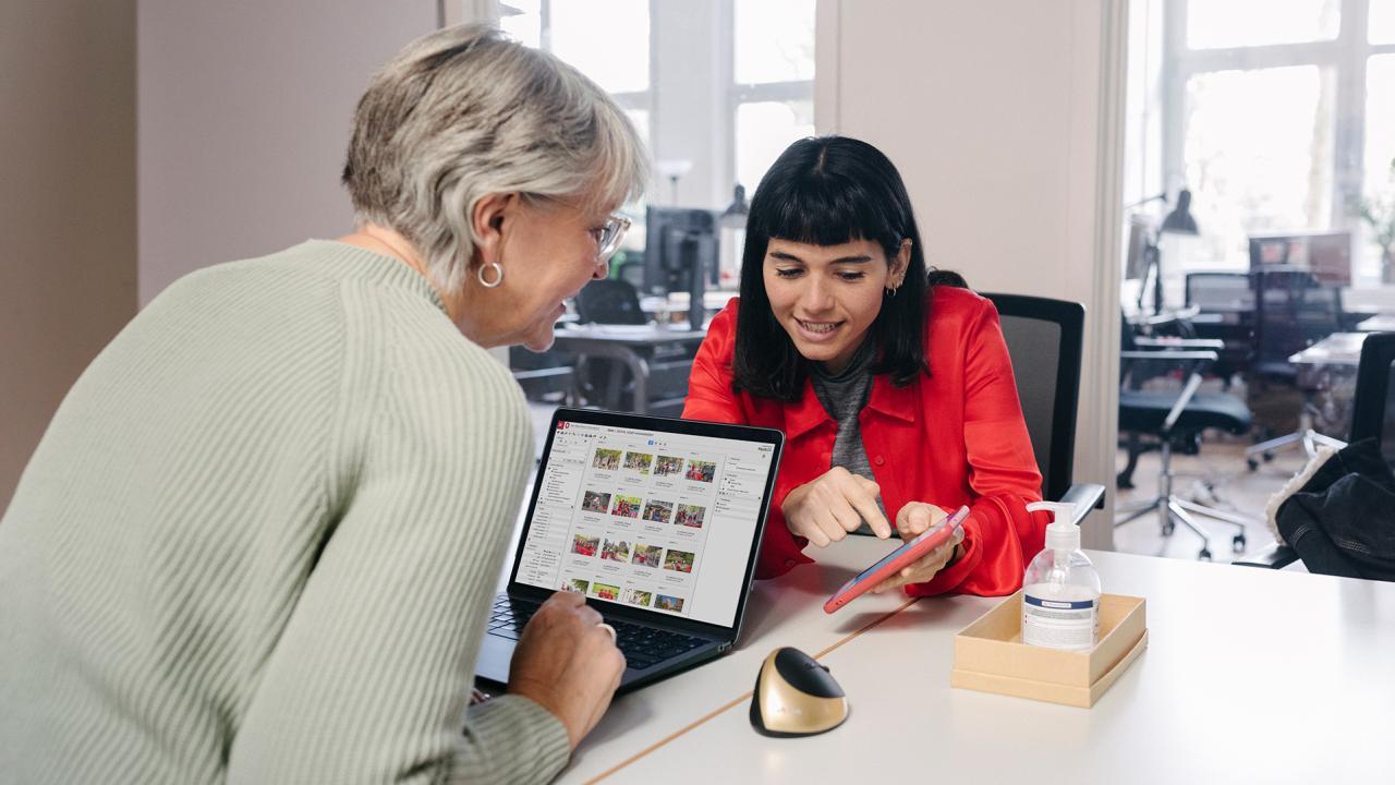 Two individuals reviewing Ohio State brand graphics on a laptop.