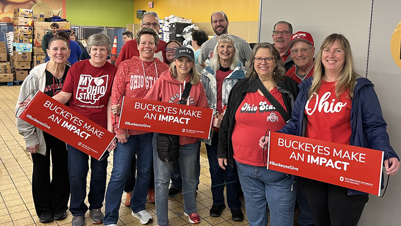 Group of Buckeyes in their Ohio State clothing holding Buckeyes Make An Impact signs.